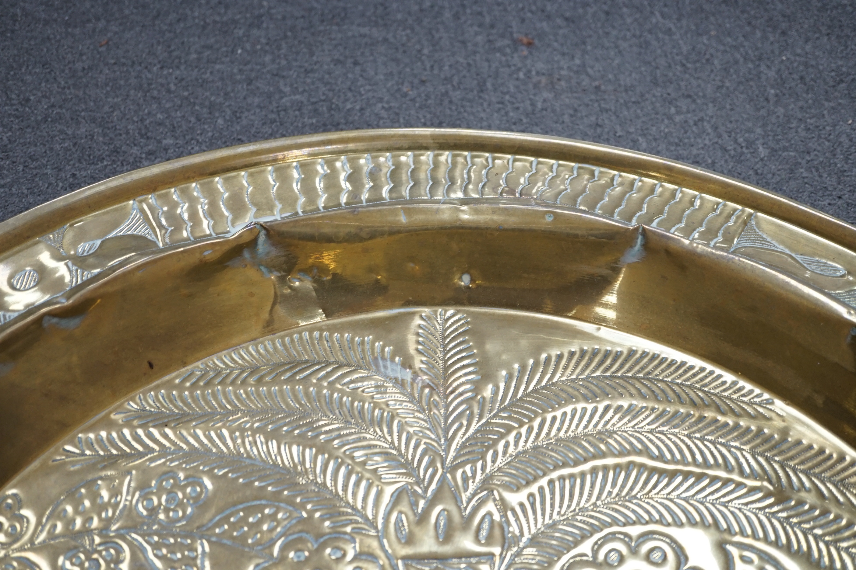 An embossed brass table top/ tray, 74cm diameter